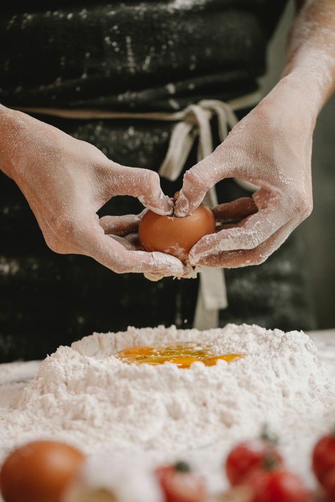 Chef cracking egg into flour