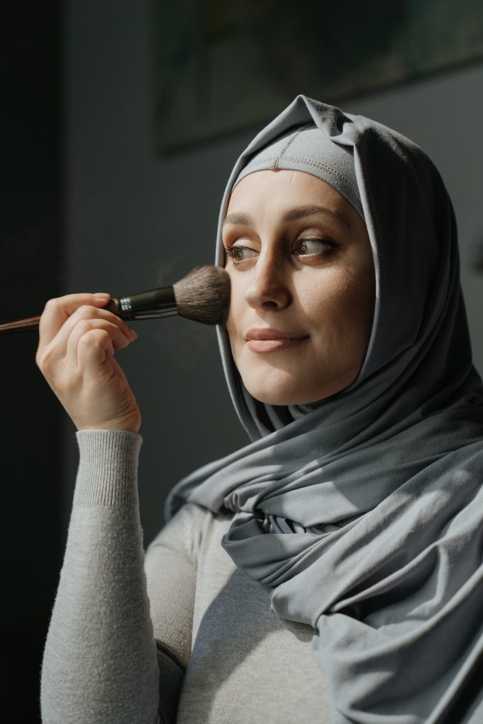 Woman wearing hijab putting on makeup